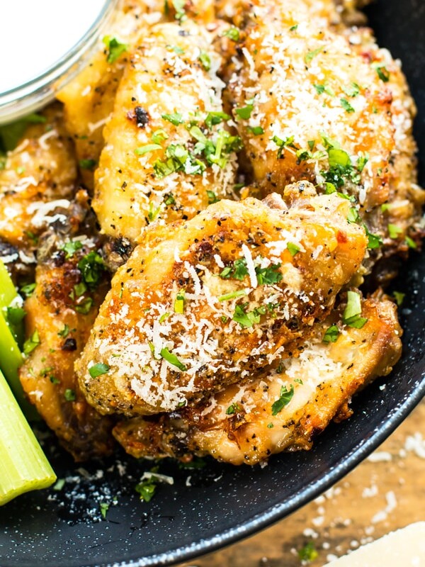 Garlic Parmesan baked chicken wings in a black bowl next to ranch dressing.