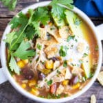 Crock-Pot chicken tortilla soup with fresh cilantro, sliced avocados, and sour cream on top.