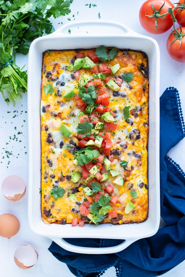 Mexican Breakfast Casserole is served from a white casserole dish on the counter.