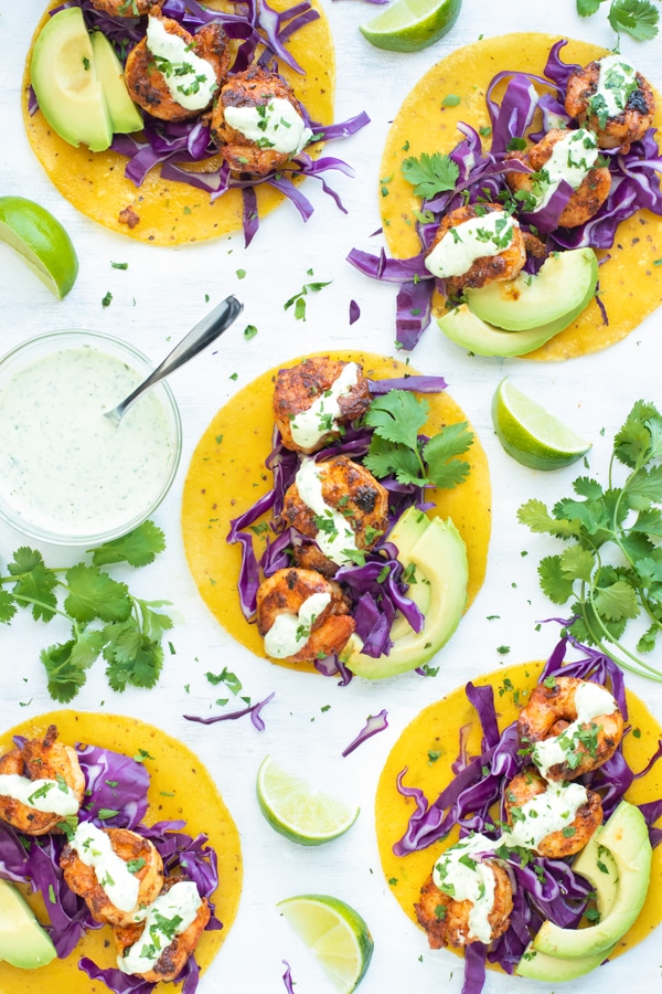 Easy Blackened Shrimp Tacos for dinner on a white table with sauce.