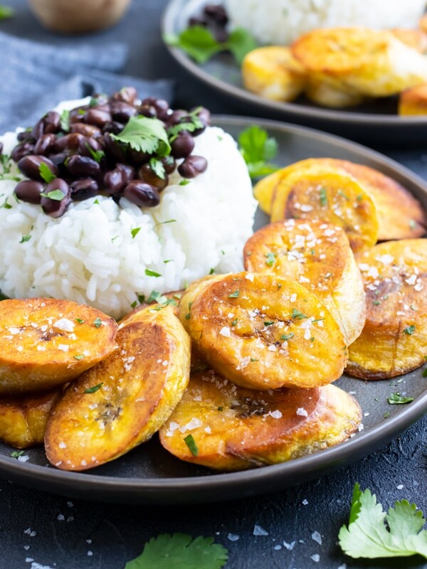 Fried plantains on a plate with rice and beans.