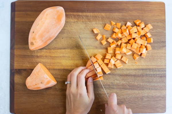 A peeled sweet potato is cut into cubes.