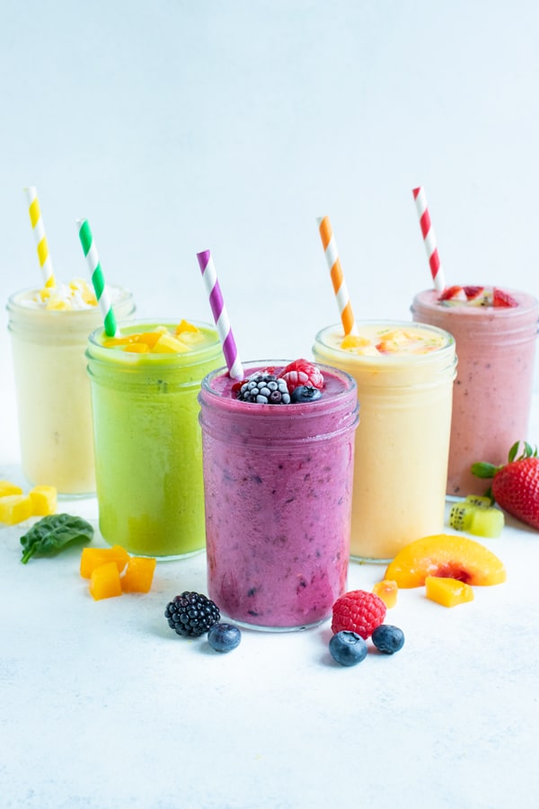 5 différents types de recettes de smoothies aux fruits surgelés sont fixés sur le comptoir.
