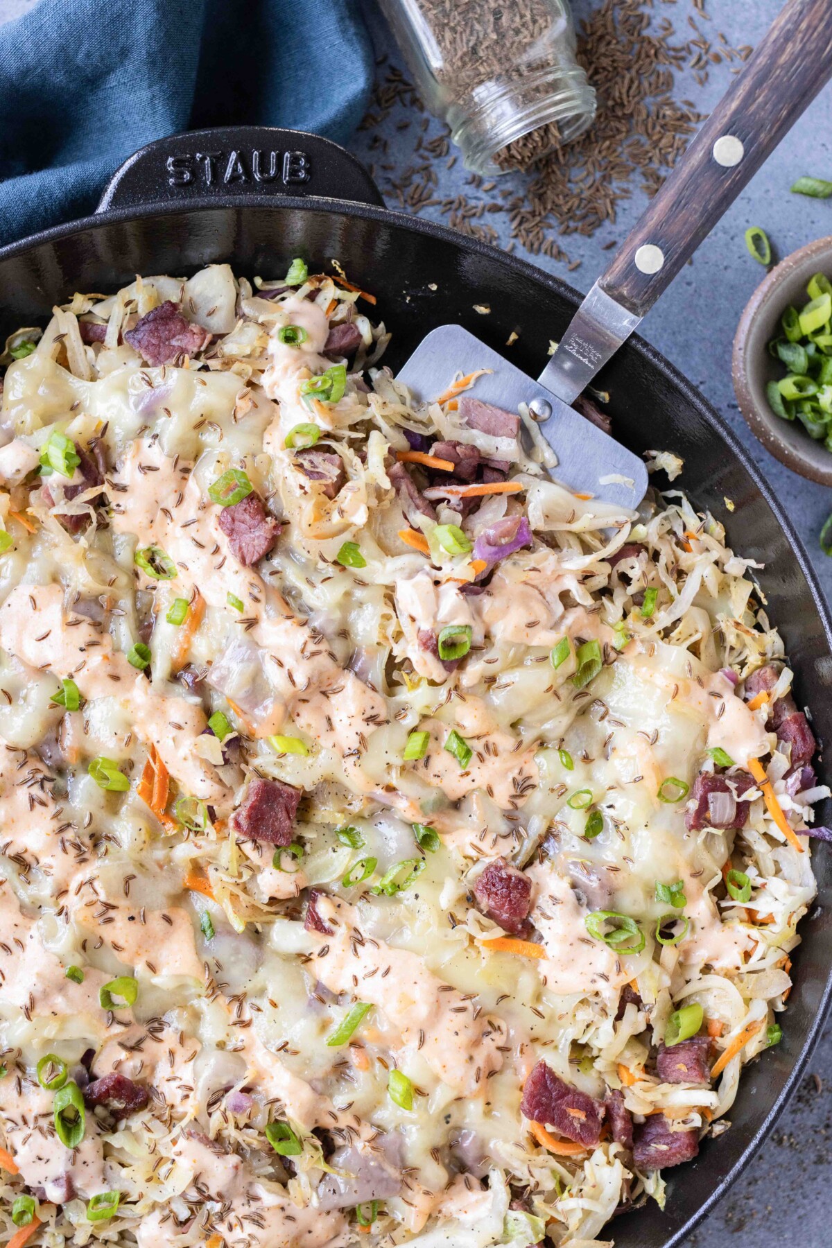 A Reuben in a bowl is being served up with a spatula with Thousand Island dressing.