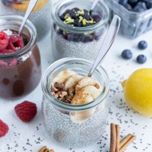 Mason jars of chia seed pudding are shown on the counter in different flavors.