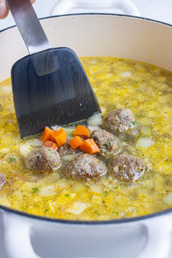 Meatballs are mixed into the pot of broth and vegetables.