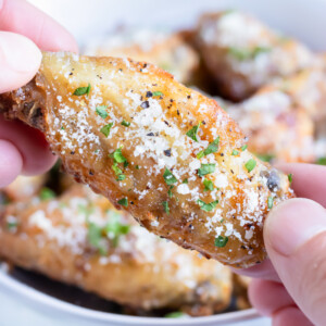 Crispy air fryer chicken wings are being held by two hands.