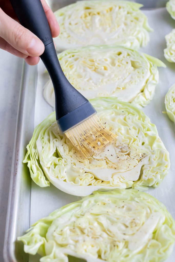 Cabbage steak is brushed with a garlic sauce before roasting.