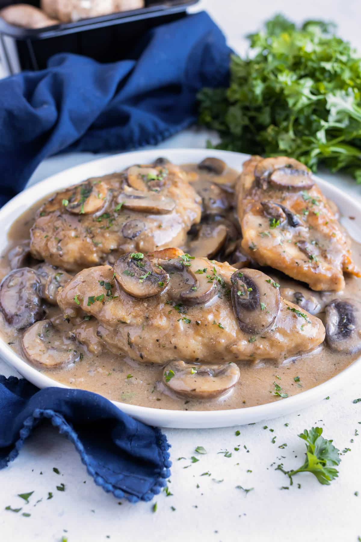 A serving of this copycat Olive Garden Chicken Marsala recipe is put on a white plate on the counter.