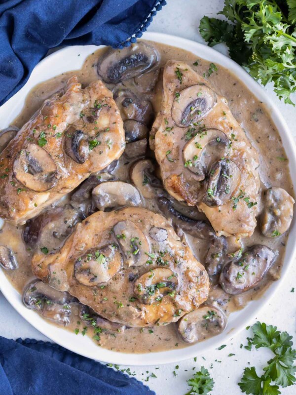 An Olive Garden Chicken Marsala copycat recipe is being served on a white plate next to a blue napkin.