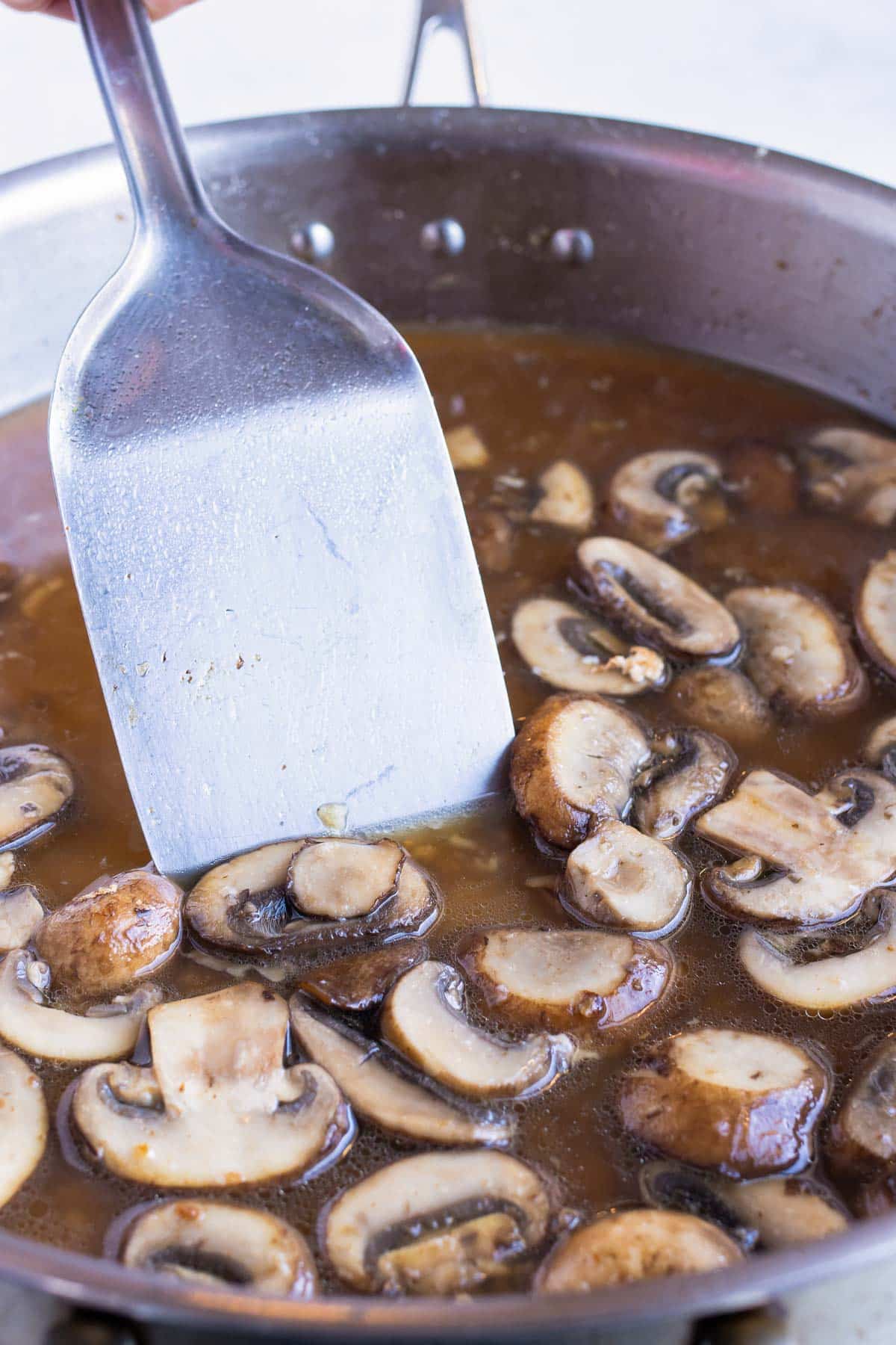 Broth and wine are added to the pan of mushrooms.