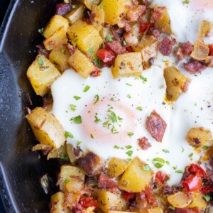 A corned beef hash and eggs recipe is served in a cast-iron skillet.