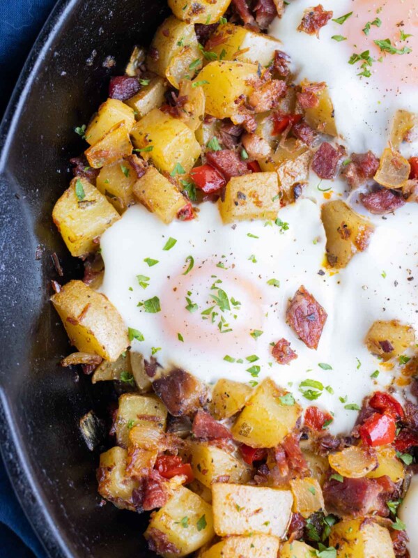 A corned beef hash and eggs recipe is served in a cast-iron skillet.