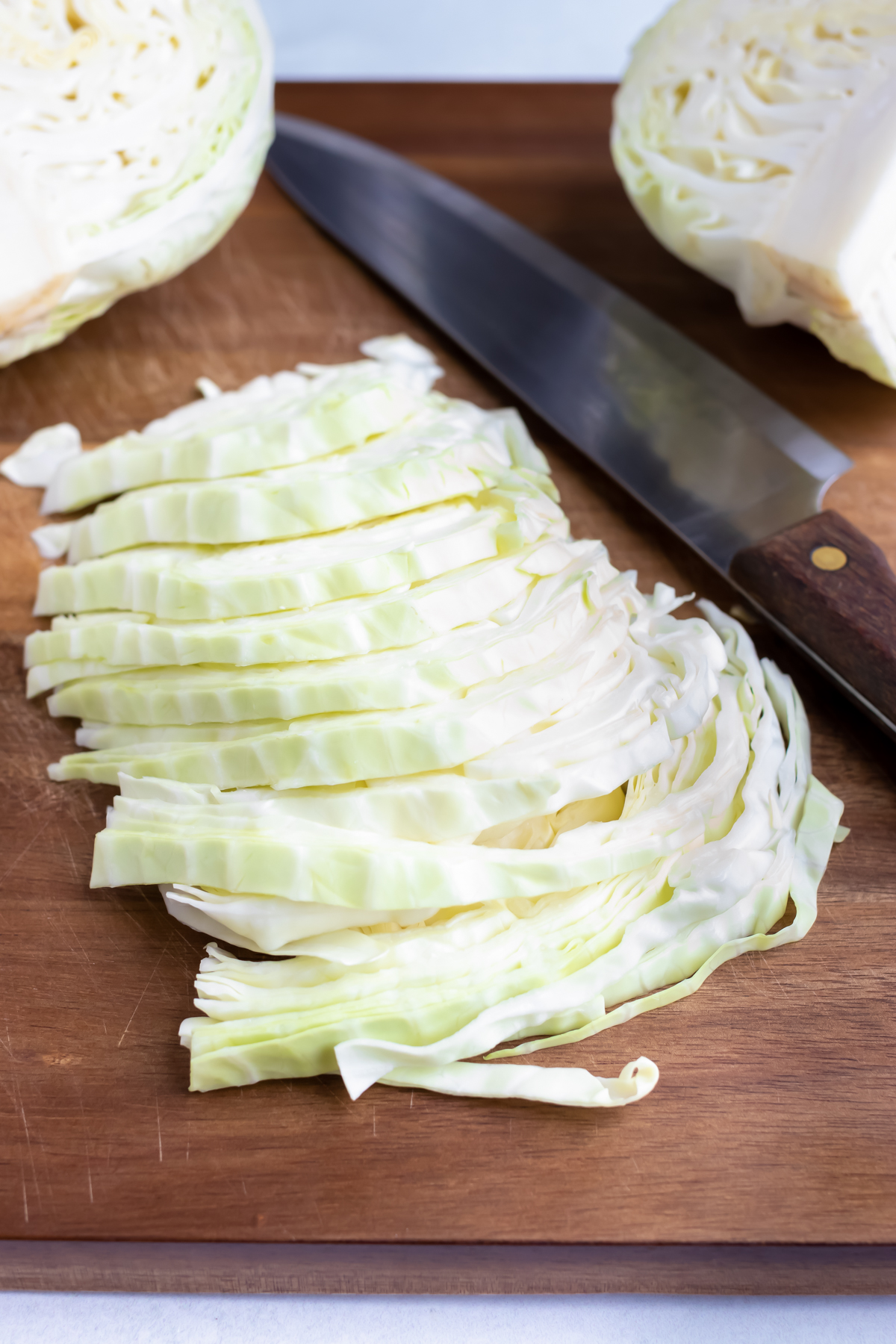 Thinly shredded cabbage is on a cutting board.