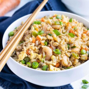 Chopsticks are shown with a bowl filled with easy shrimp fried rice.