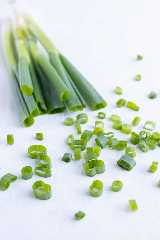 Whole green onions are set beside sliced green onions.