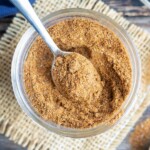 Homemade taco seasoning recipe in a glass container with a silver spoon scooping some out.