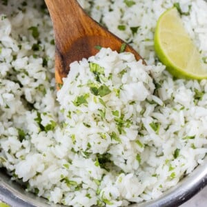 An easy cilantro lime rice recipe that is a copycat of Chipotle's in a metal pot with a wooden spoon and lime wedges.