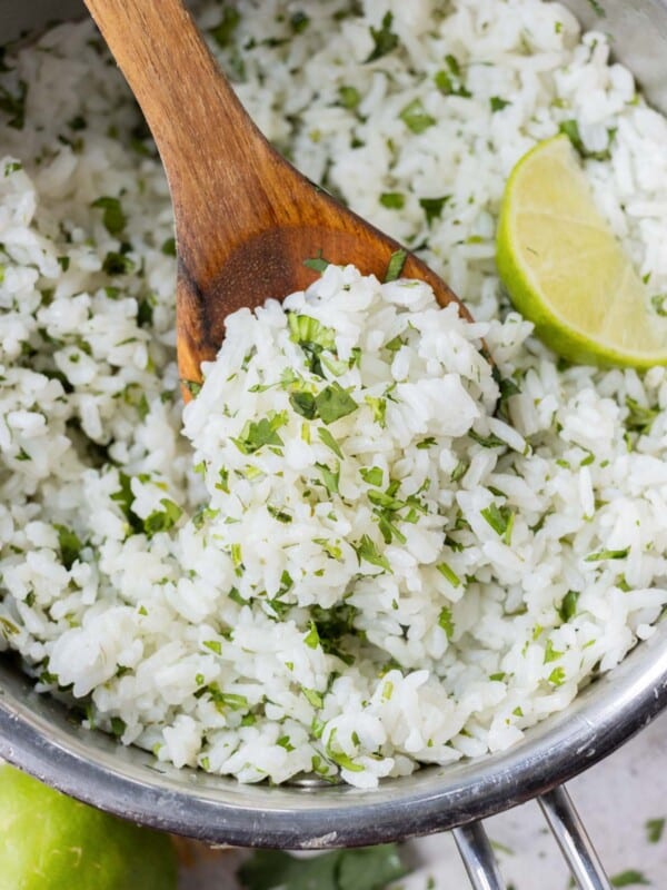 An easy cilantro lime rice recipe that is a copycat of Chipotle's in a metal pot with a wooden spoon and lime wedges.