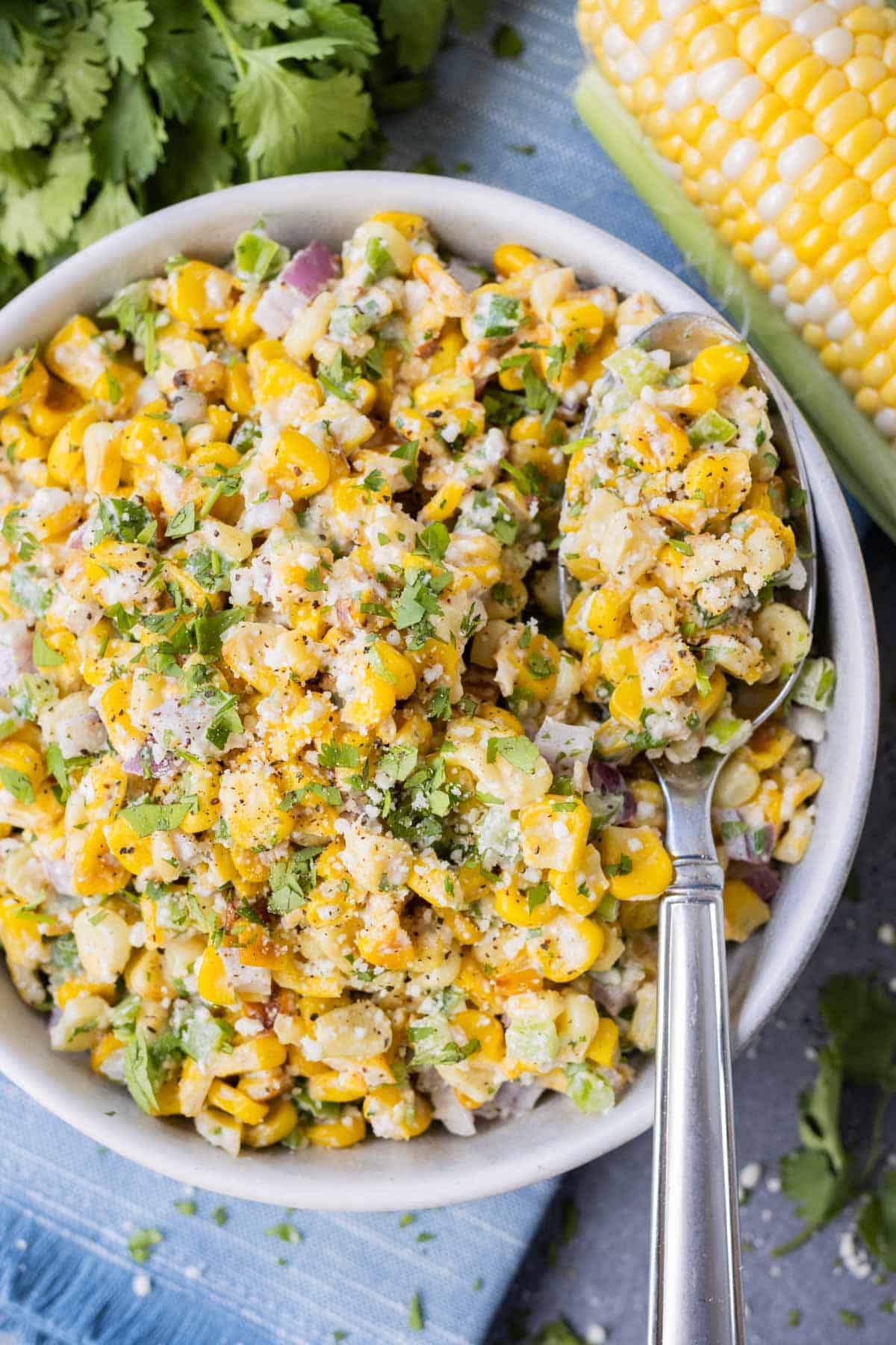 Skillet Mexican Street Corn Salad RECIPE served in a white bowl with a silver spoon.