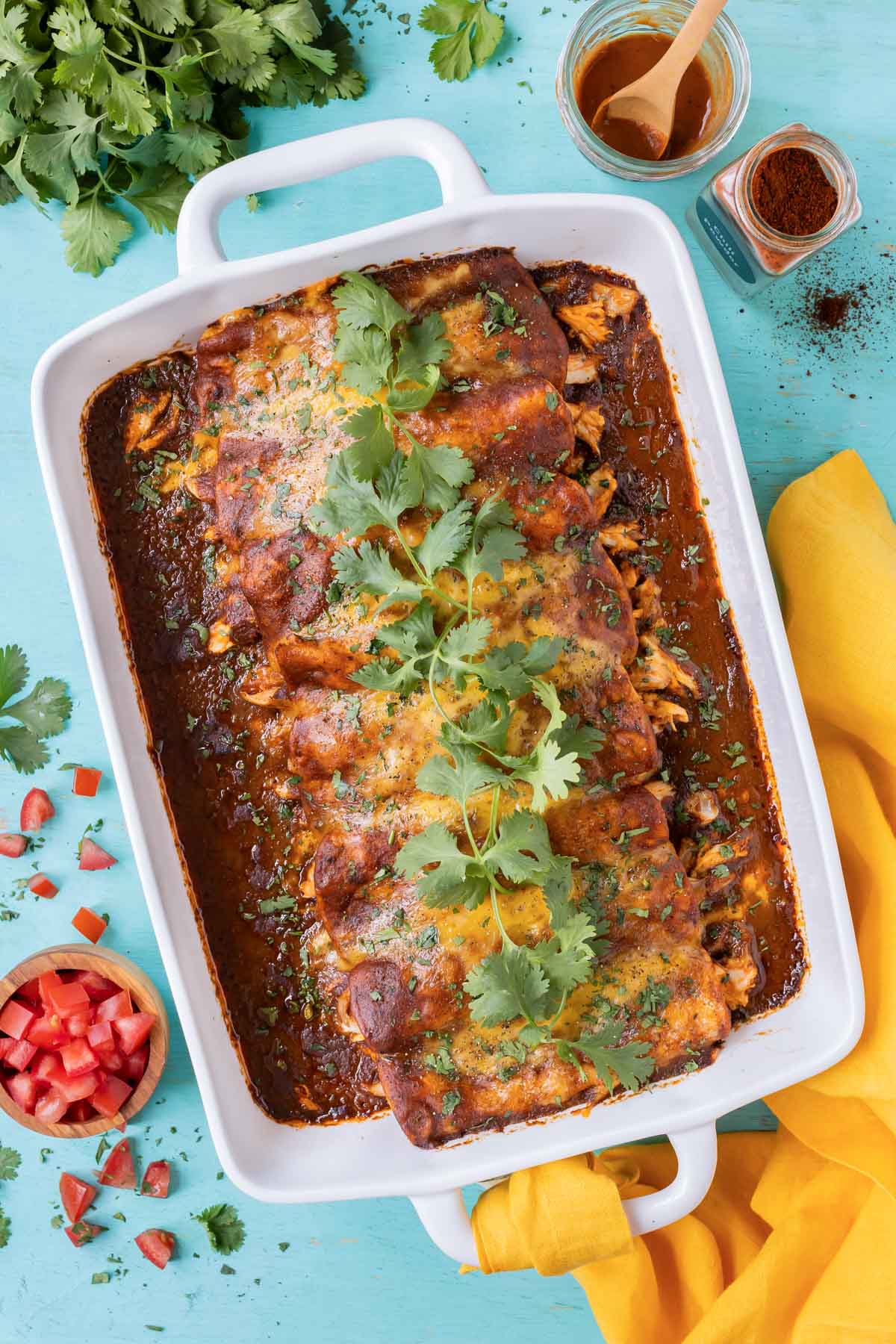 A tray full of an easy homemade chicken enchiladas recipe with cheese and topped with cilantro.