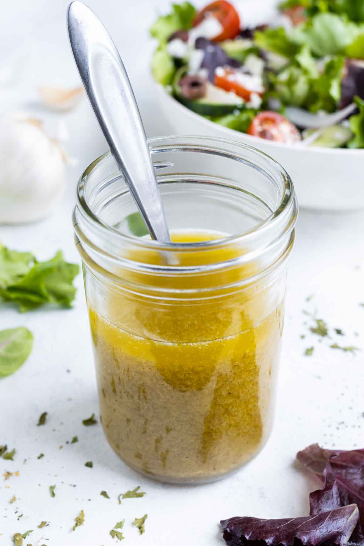 Greek salad dressing in a jar is served with a spoon.