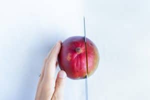 Cutting just to the right of the midline of a mango to remove the cheek.