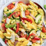 A large white bowl full of an easy and healthy roasted vegetable pasta with tomatoes, asparagus, and bell peppers.