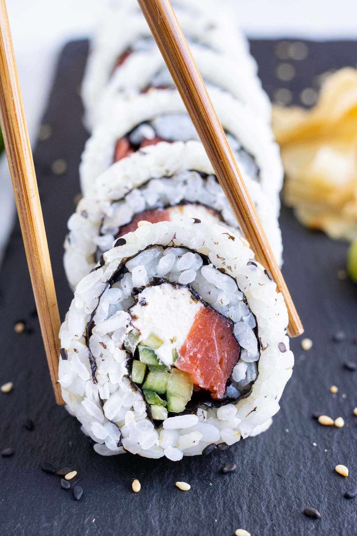 Philadelphia Sushi Roll RECIPE served on a black plate with chopsticks.