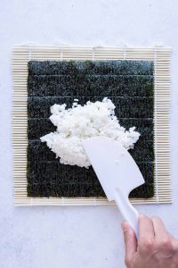 Spatula is used to spread the rice on the nori.