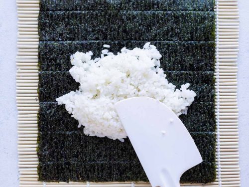 Spatula is used to spread the rice on the nori.