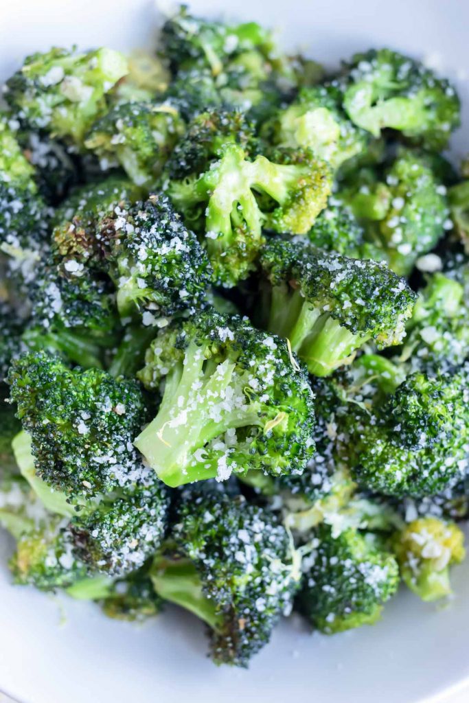 Air fryer broccoli is topped with parmesan cheese and served in a bowl.