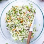 A glass bowl is filled with cabbage and other ingredients for this taco slaw.