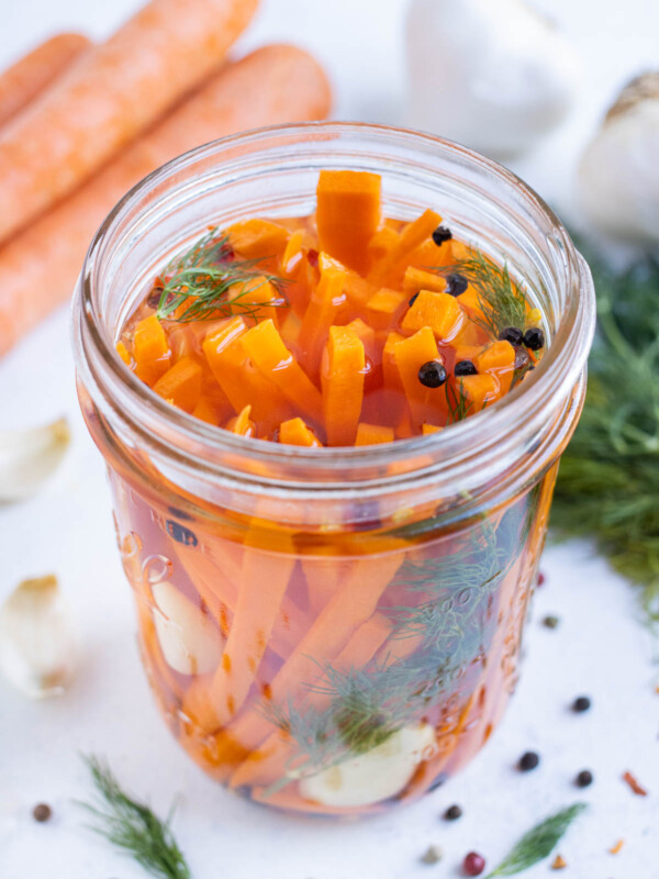 Quick pickled carrots in a brining solution in a jar.