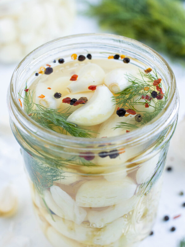 A closeup of garlic and brining solution in a glass jar.