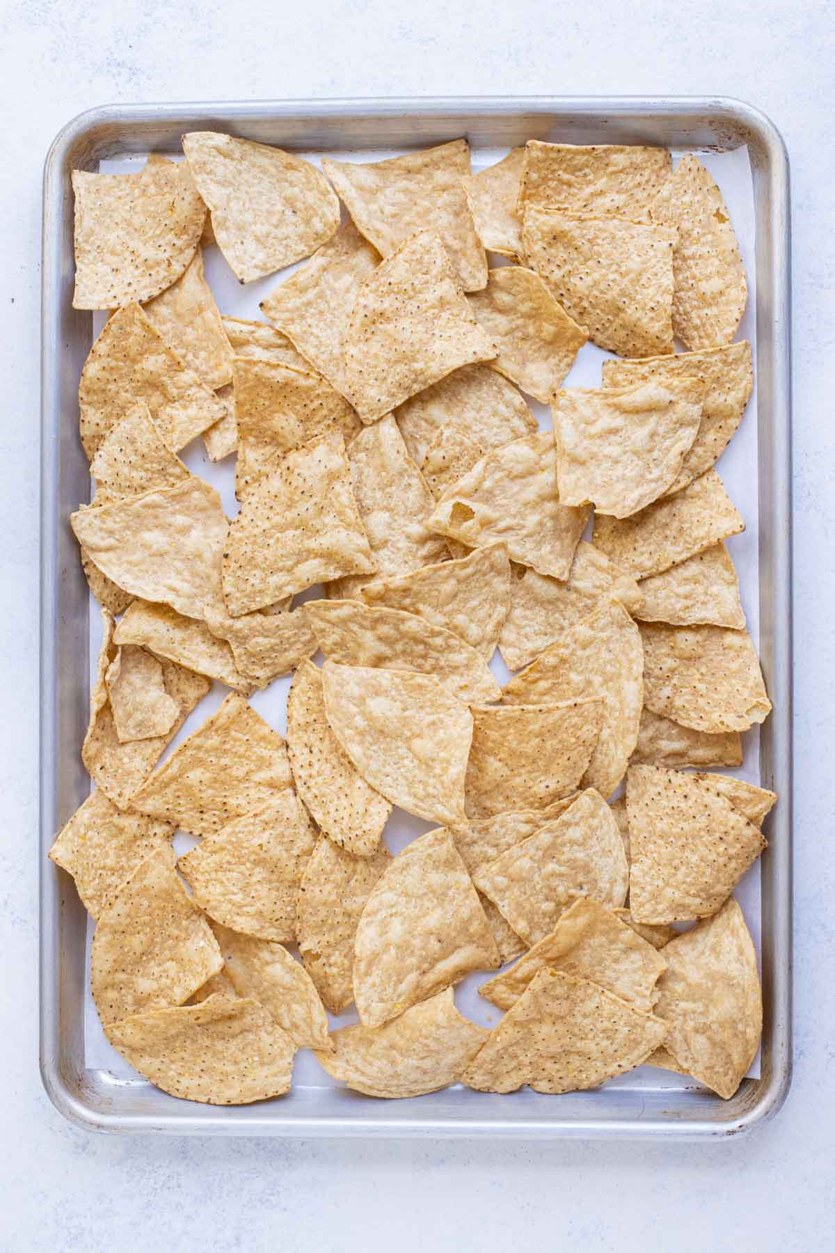 Chips are layered on a sheet pan for nachos.