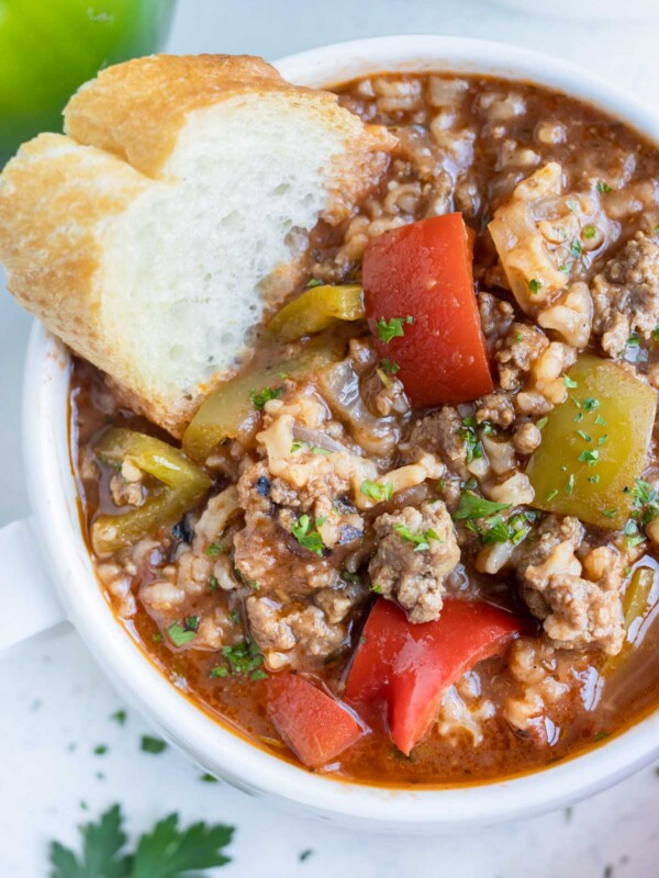 A bowl of soup is shown loaded with ground beef, bell peppers, and rice.