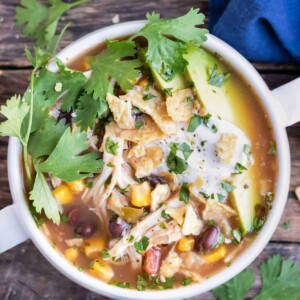 Crock-Pot chicken tortilla soup with fresh cilantro, sliced avocados, and sour cream on top.