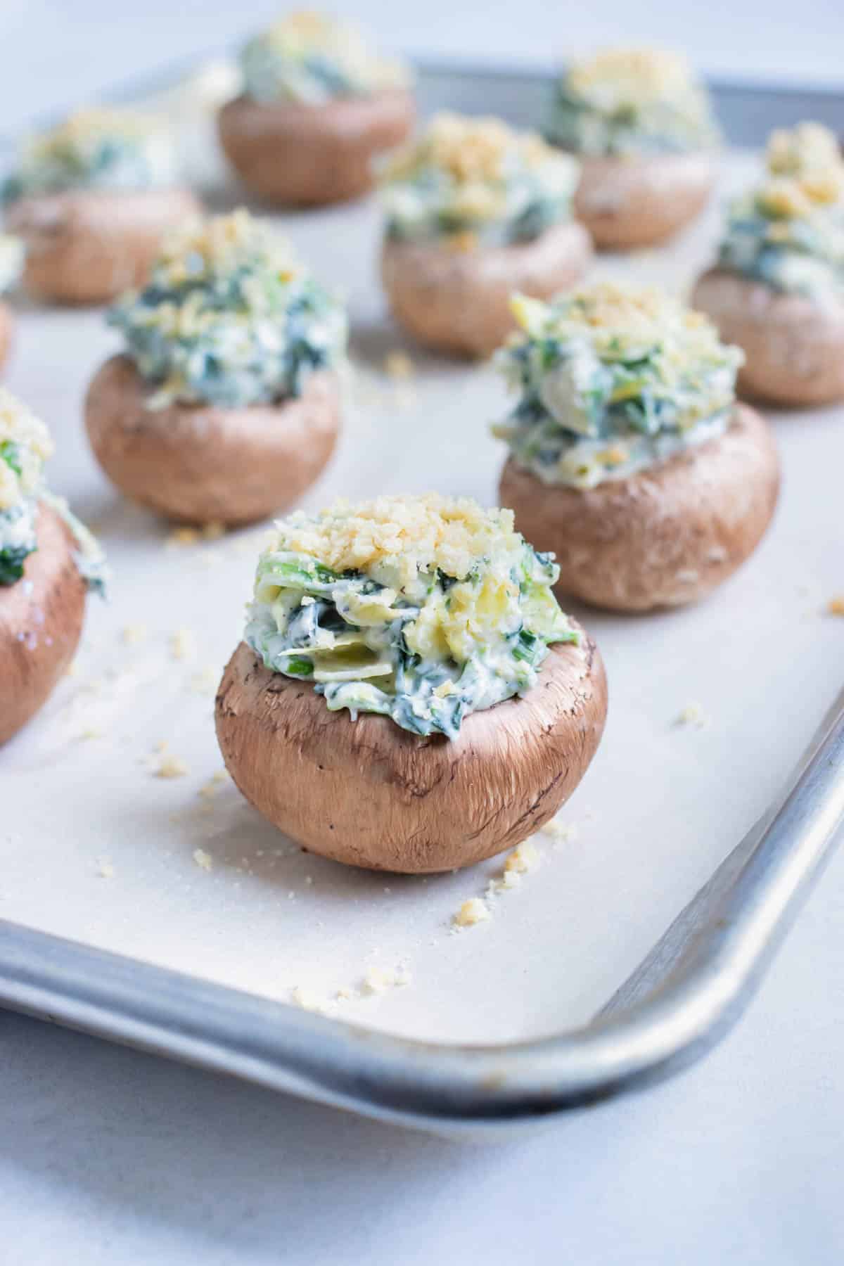 Stuffed mushrooms are placed on a baking sheet and baked in the oven.