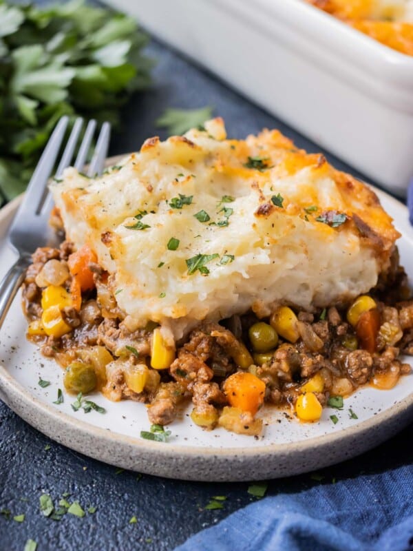 A piece of a traditional shepherd's pie recipe on a white plate with a fork for a weeknight dinner.