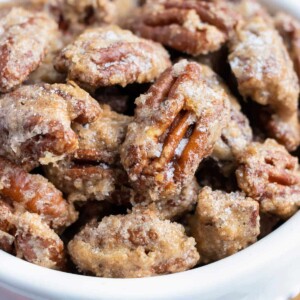 Cinnamon sugar pecans are in a white serving bowl for the holidays.