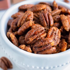 Oven toasted pecans are put in a bowl on the counter for a keto snack.