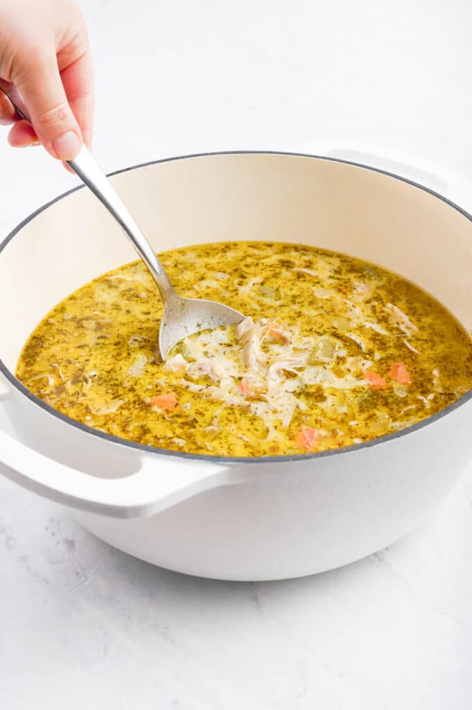 A spoon stirs the starch slurry into the soup.