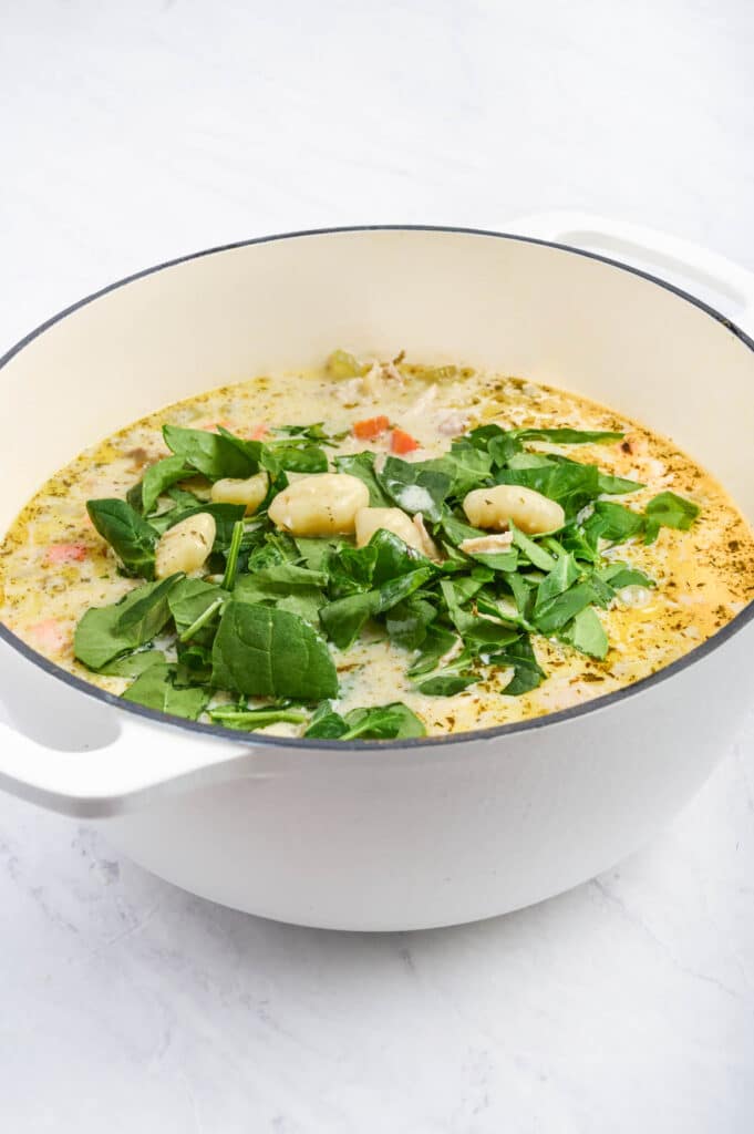 Spinach leaves and gnocchi are added to the creamy soup base.