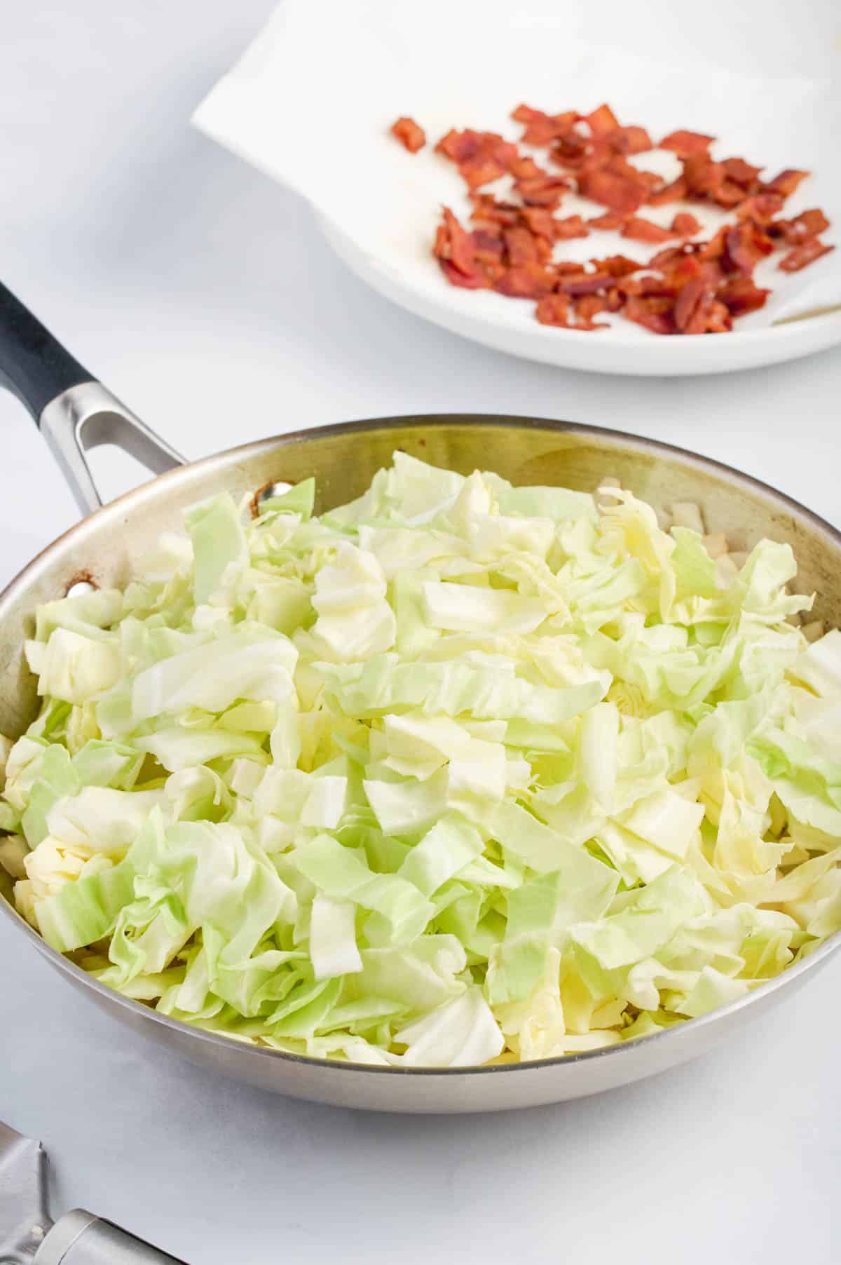 Half of the cabbage is added to the skillet.