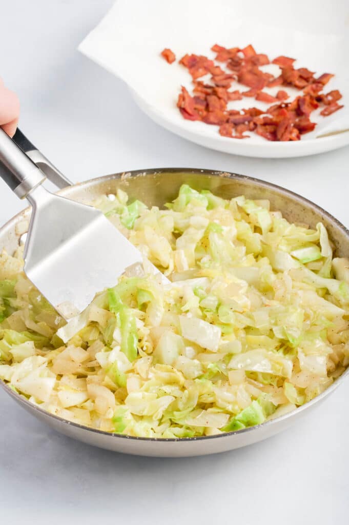 A spatula stirs the cabbage.