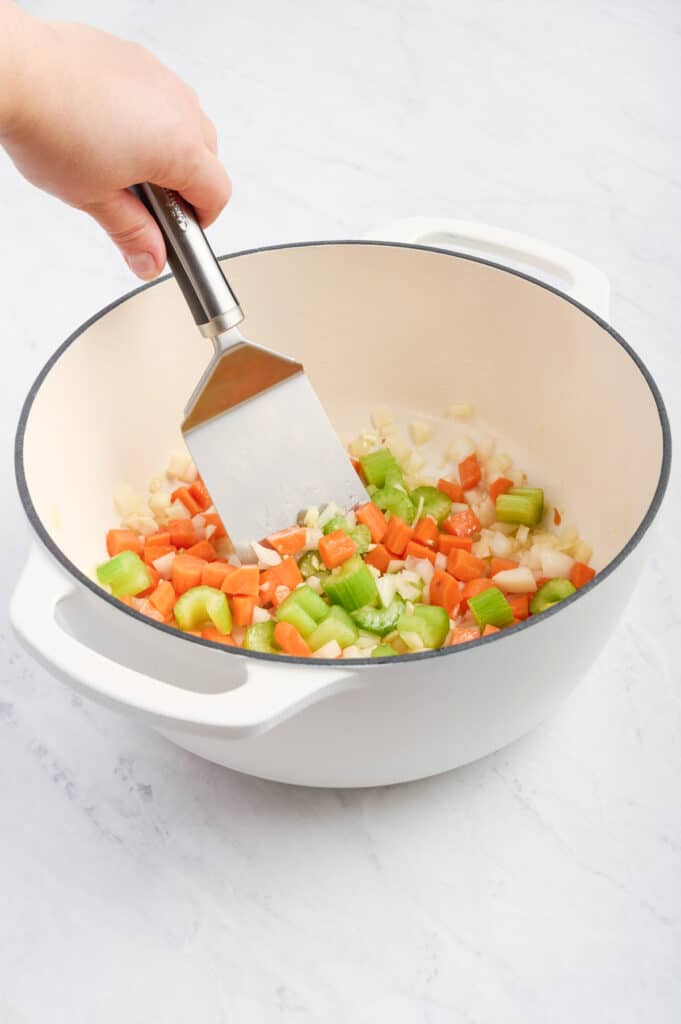 A spatula stirs the garlic and veggies.