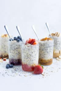 Multiple glass mason jars full of different flavors of overnight oats recipes.