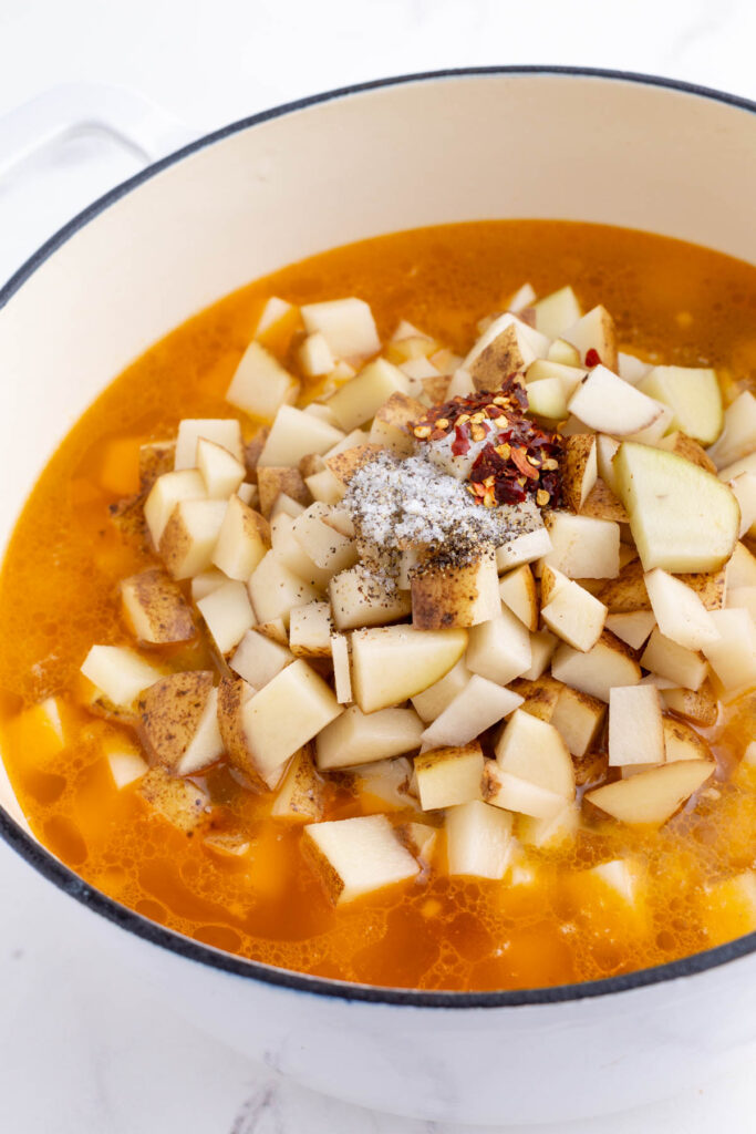 Potatoes and spices are added to the broth mixture.