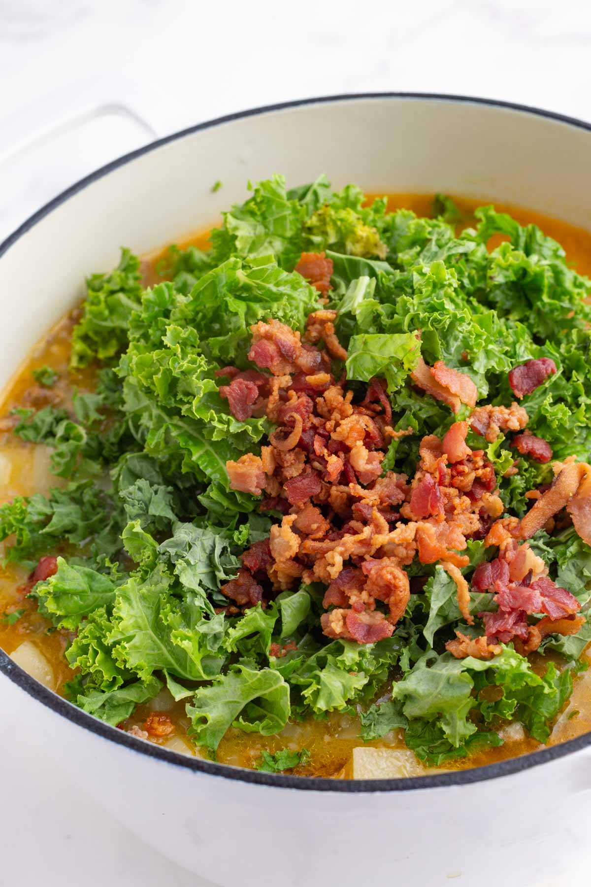 Chopped kale and cooked bacon are added to the soup.